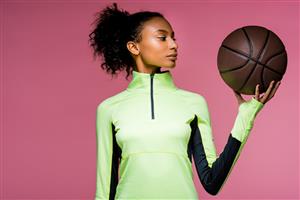 A Woman Holding A Basketball In Front Of A Pink Background